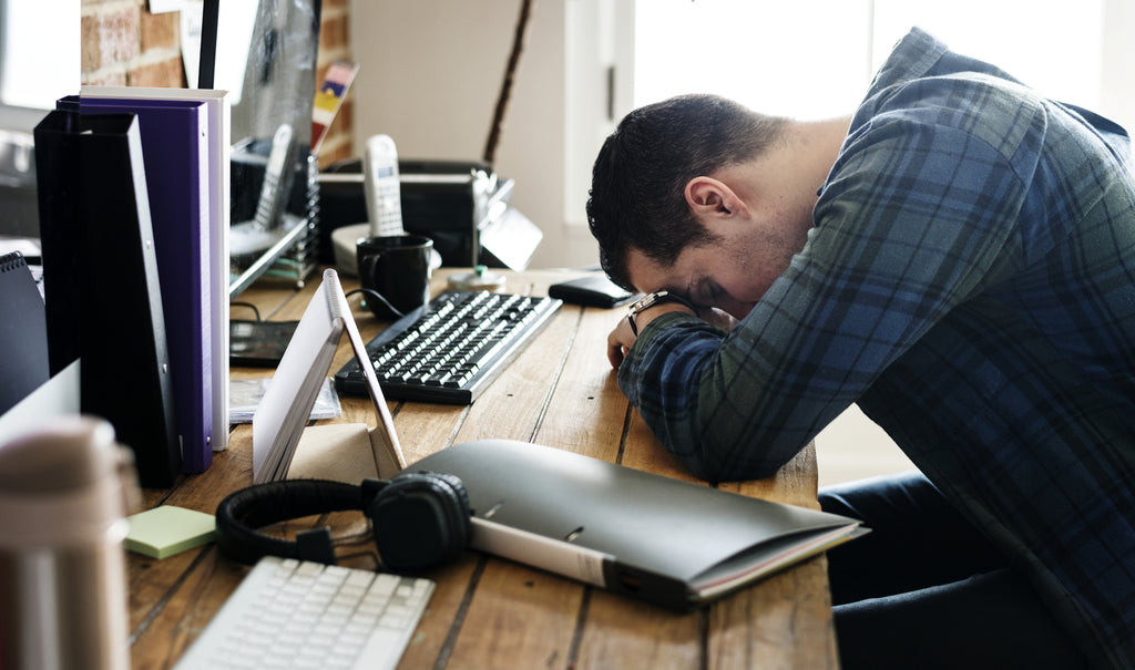 Tired man napping on the working desk | Experience CBD